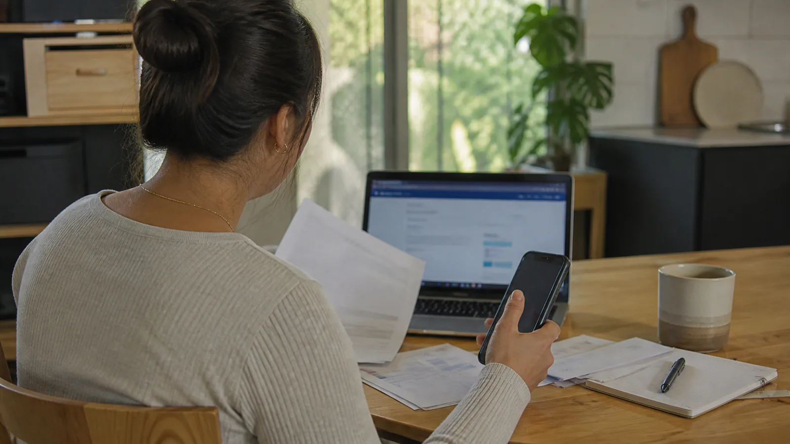 Illustrative editorial scene of an employee checking employment papers and an online insurer search at home.