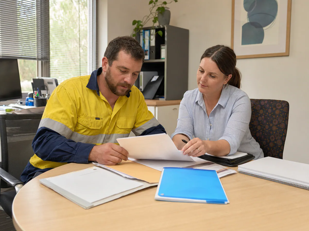 A worker and adviser assembling an incident report, capacity certificate and wage records for a claim.